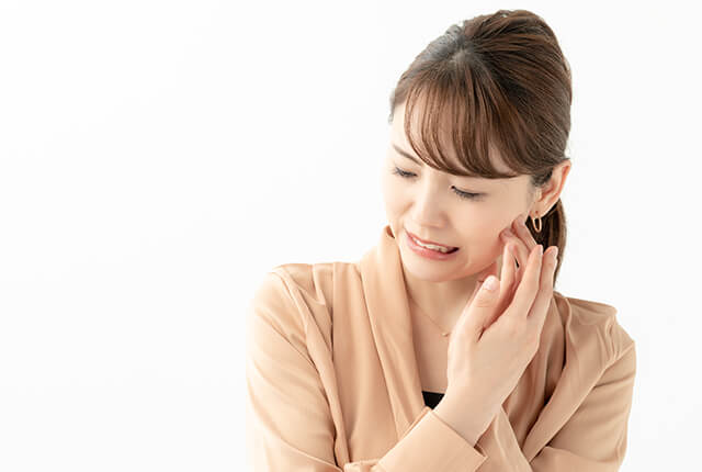 痛そうに頬を押さえている若い女性