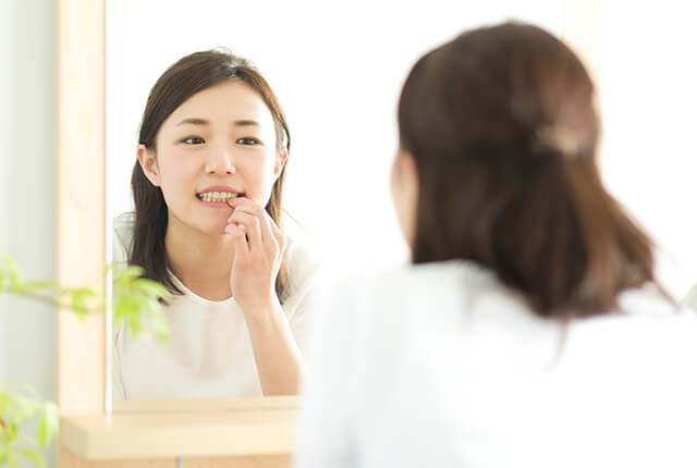 自分の歯のチェックをしている女性
