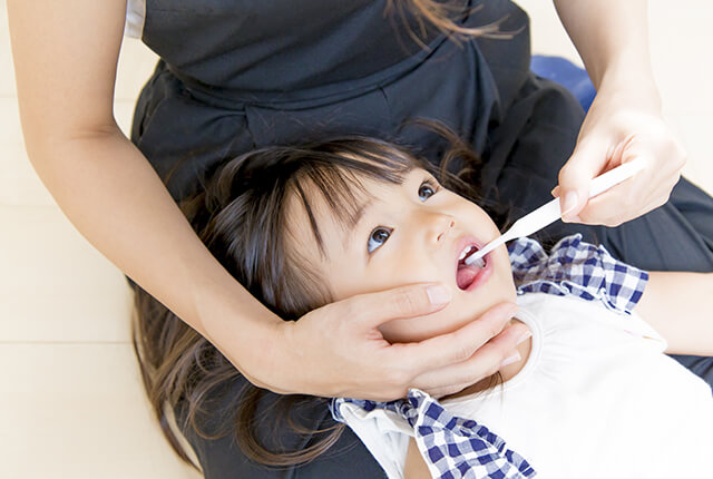 親が子供の歯を磨いている様子